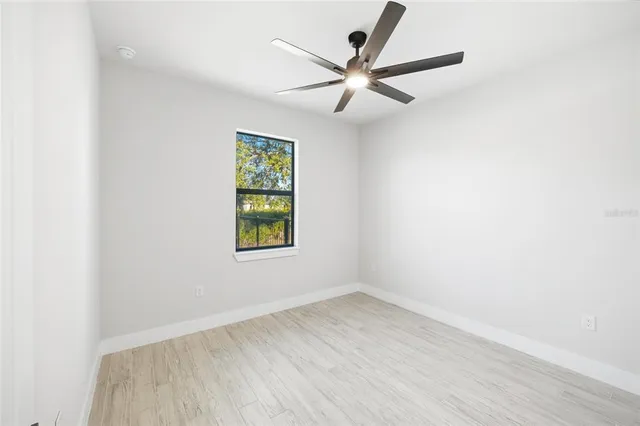 an empty room with a window and a ceiling fan