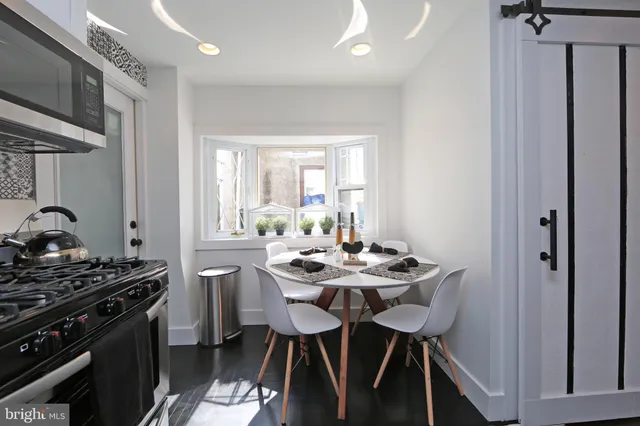 a kitchen with stainless steel appliances a stove a sink dishwasher a microwave oven with a dining table and chairs