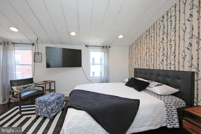 a living room with a bed furniture and a flat screen tv