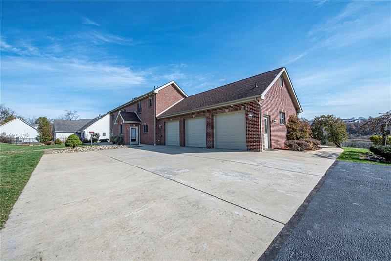 240 Durst Road Irwin, PA 15642 - Photo 22 of 24 Plenty of parking. Long paved driveway is newer. Extra large concrete area and mandoor to 3 car attached garage. Concrete walkway to front door. Doorway also shown leading into kitchen.