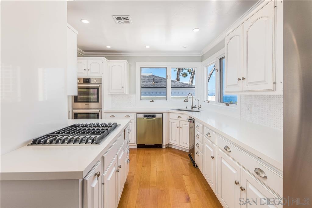 862 Prospect Street, Unit 1 La Jolla, CA 92037 - Photo 9 of 25 a kitchen with stainless steel appliances a sink stove and cabinets
