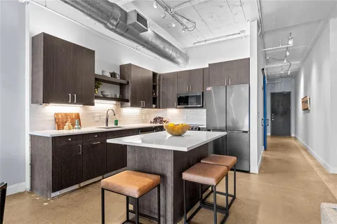 a kitchen with stainless steel appliances a table chairs refrigerator and microwave