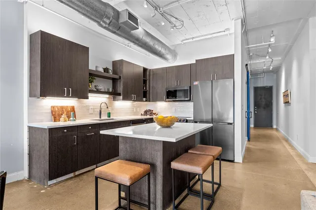 a kitchen with stainless steel appliances a table chairs refrigerator and microwave