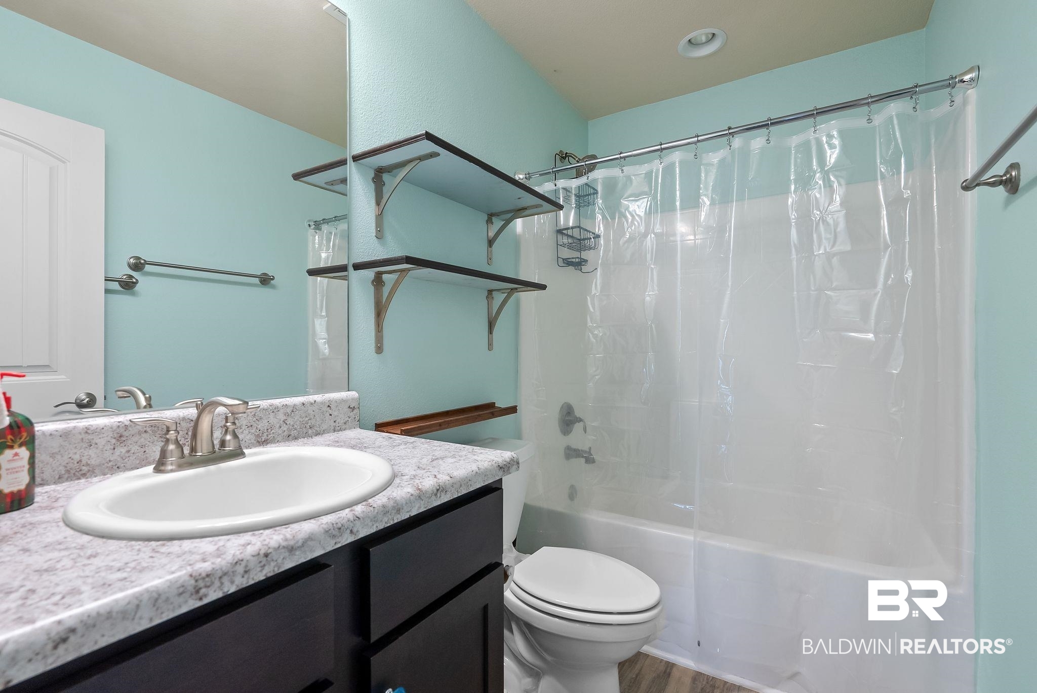 22076 Garland Loop Silverhill, AL 36576 - Photo 17 of 27 Bathroom featuring a built-in tub with shower, single vanity with a white oval sink, and dark wood-finish cabinetry