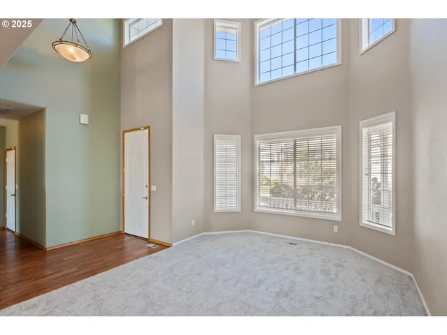 a view of an empty room with wooden floor and windows