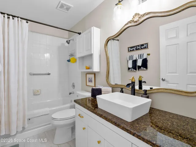 a bathroom with a granite countertop sink a toilet and shower