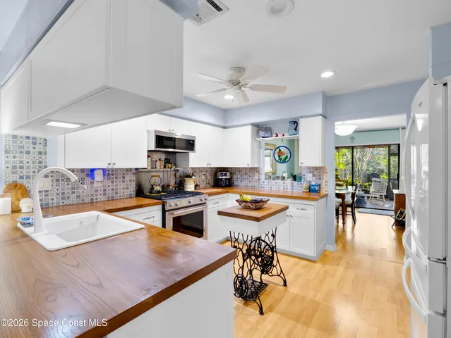 a dining hall with stainless steel appliances granite countertop a sink a stove and chairs with wooden floor