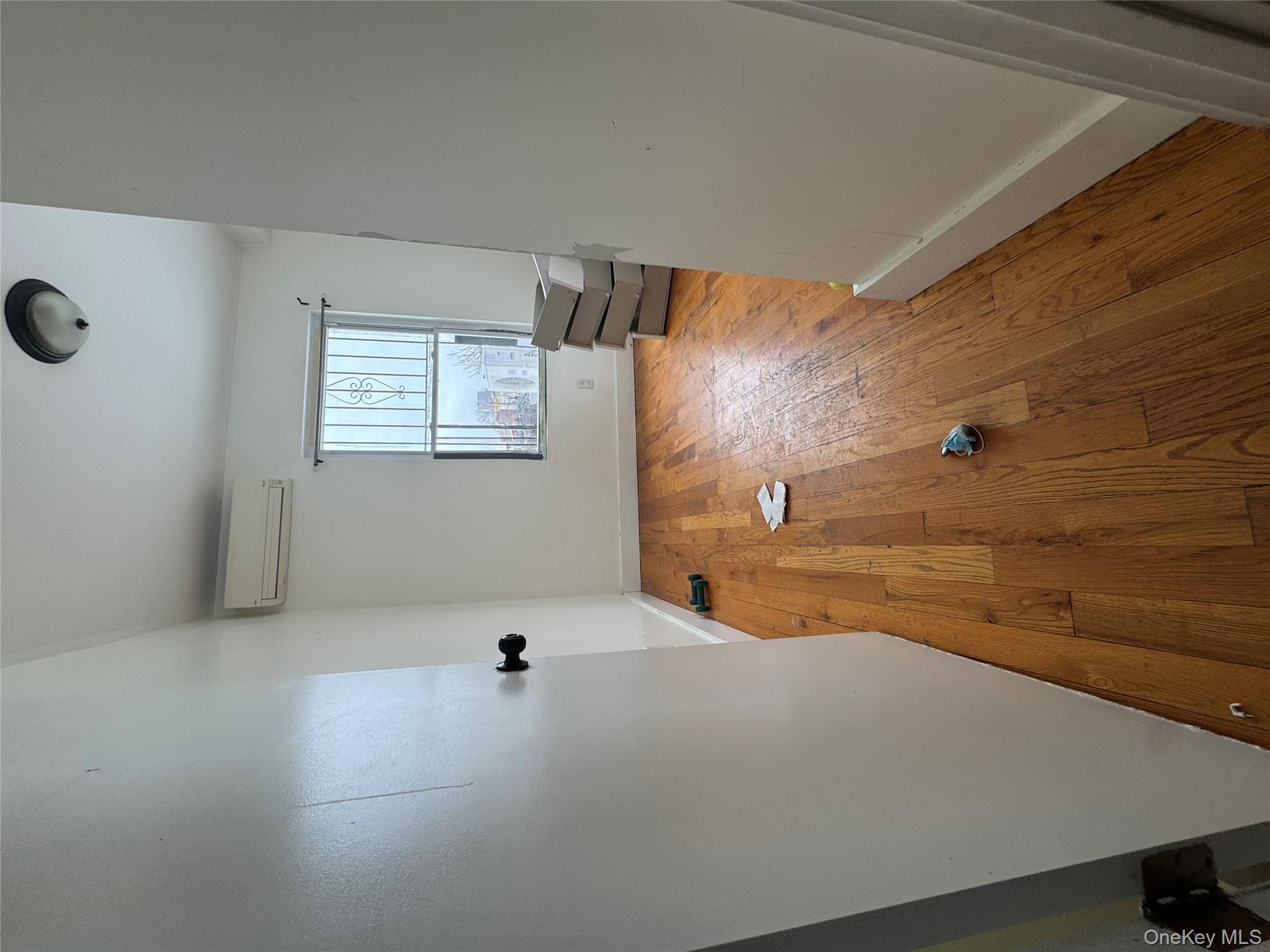 96-02 Northern Boulevard, Unit 3B Queens, NY 11368 - Photo 2 of 5 an empty room with wooden floor and windows