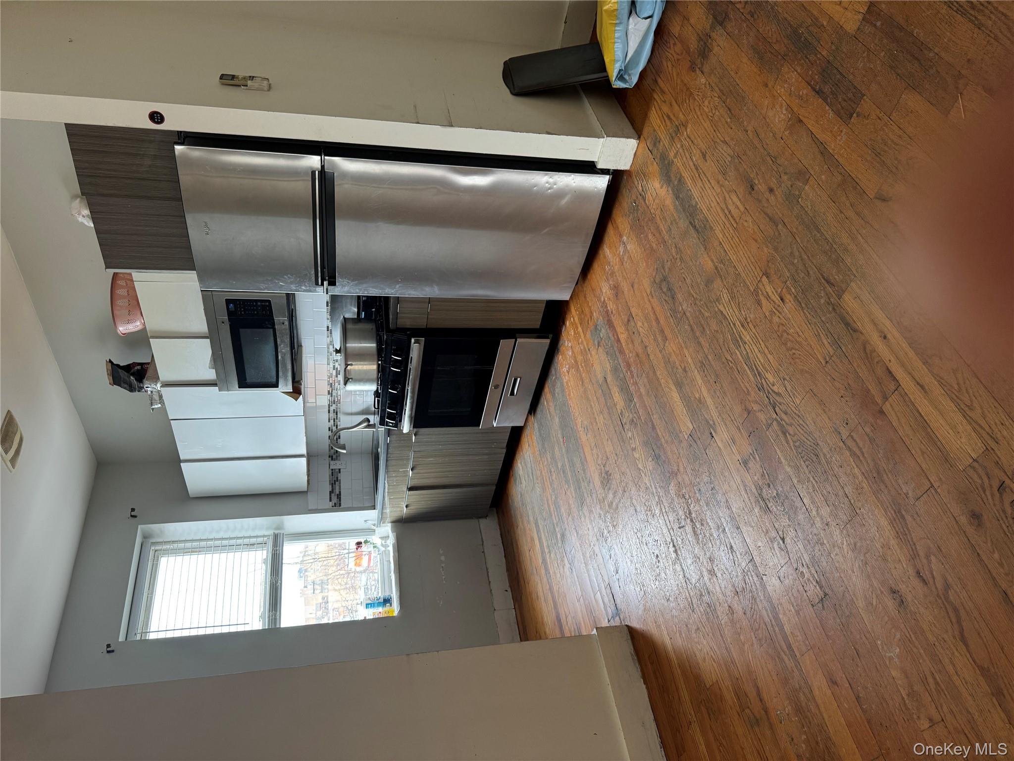 96-02 Northern Boulevard, Unit 3B Queens, NY 11368 - Photo 4 of 5 a kitchen with stainless steel appliances a refrigerator stove microwave and sink