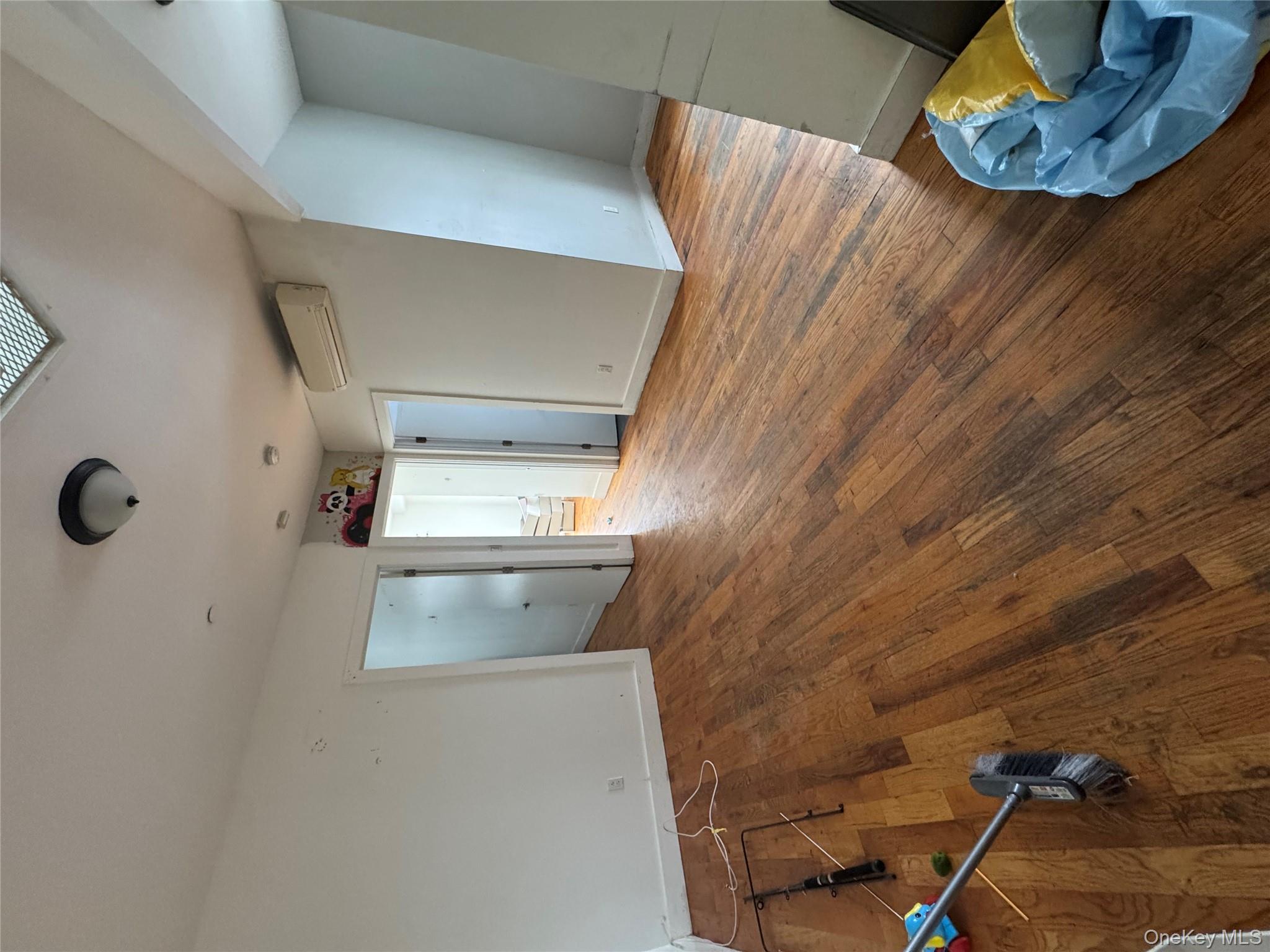 96-02 Northern Boulevard, Unit 3B Queens, NY 11368 - Photo 5 of 5 a view of an empty room with wooden floor and a window