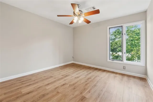 an empty room with wooden floor fan and windows