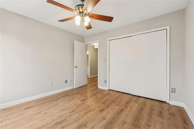 an empty room with wooden floor closet and ceiling fan