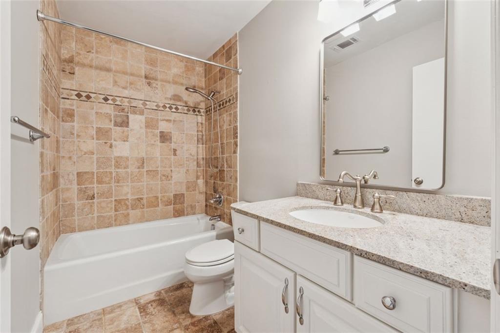 4010 Roswell Road Northeast, Unit A2 Atlanta, GA 30342 - Photo 17 of 32 a bathroom with a granite countertop sink a toilet a mirror a bathtub and shower