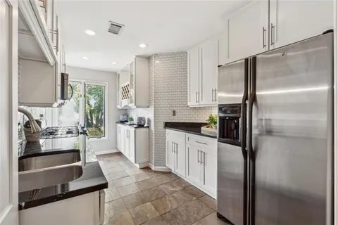 a kitchen with white cabinets and refrigerator
