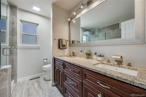 a bathroom with a granite countertop sink a toilet and a mirror