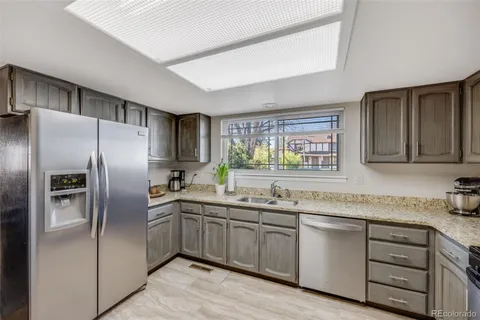 a kitchen with granite countertop stainless steel appliances a sink and a refrigerator