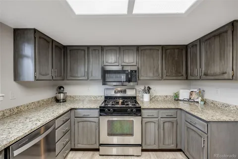 a kitchen with granite countertop wooden cabinets and a stove top oven