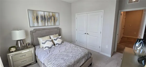 a bedroom with a bed and a lamp on dresser