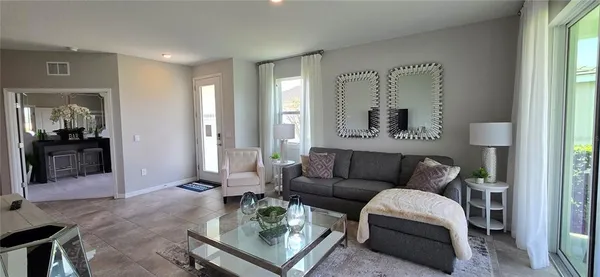 a living room with furniture and a large mirror next to a window