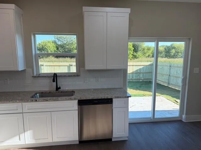 a kitchen with granite countertop white cabinets and a large window