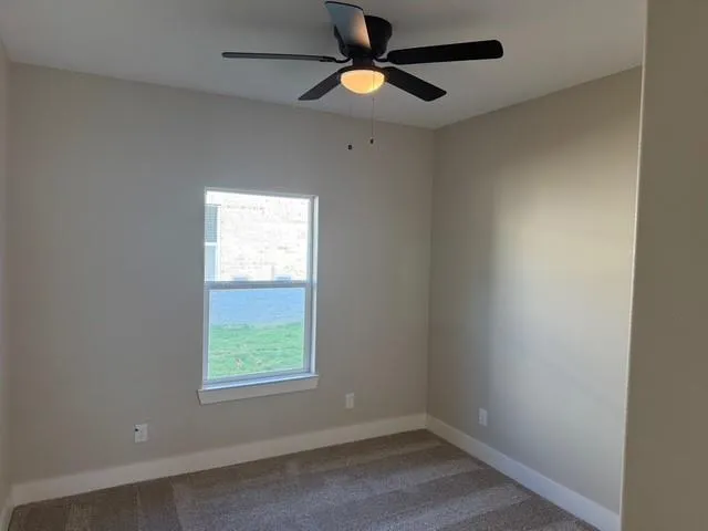an empty room with a window and a fan