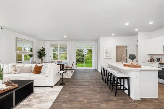 a kitchen with stainless steel appliances a dining table chairs microwave and refrigerator