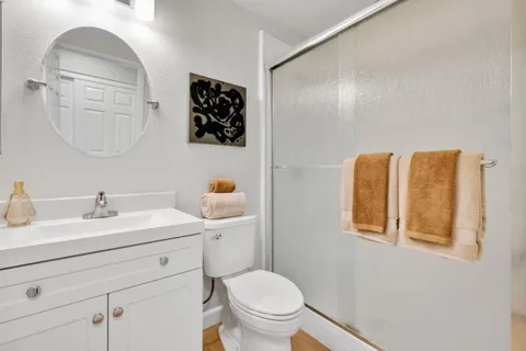 a bathroom with a toilet sink vanity granite and mirror