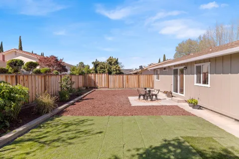 a backyard of a house with table and chairs plants