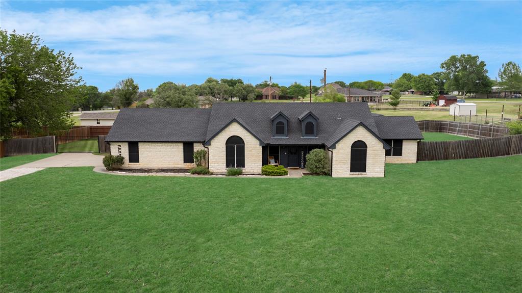 Single-story residence featuring a light brick exterior, dark shingle roof, and a prominent front yard