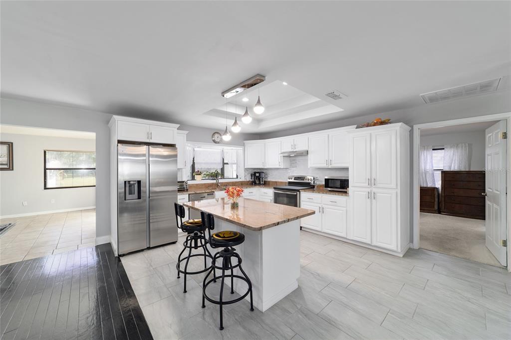 985 Northwest 73rd Terrace Ocala, FL 34482 - Photo 29 of 89 a kitchen with a refrigerator a stove oven a sink dishwasher and white cabinets with wooden floor