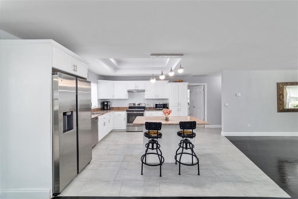 985 Northwest 73rd Terrace Ocala, FL 34482 - Photo 30 of 89 a dining room with stainless steel appliances kitchen island granite countertop a refrigerator and cabinets