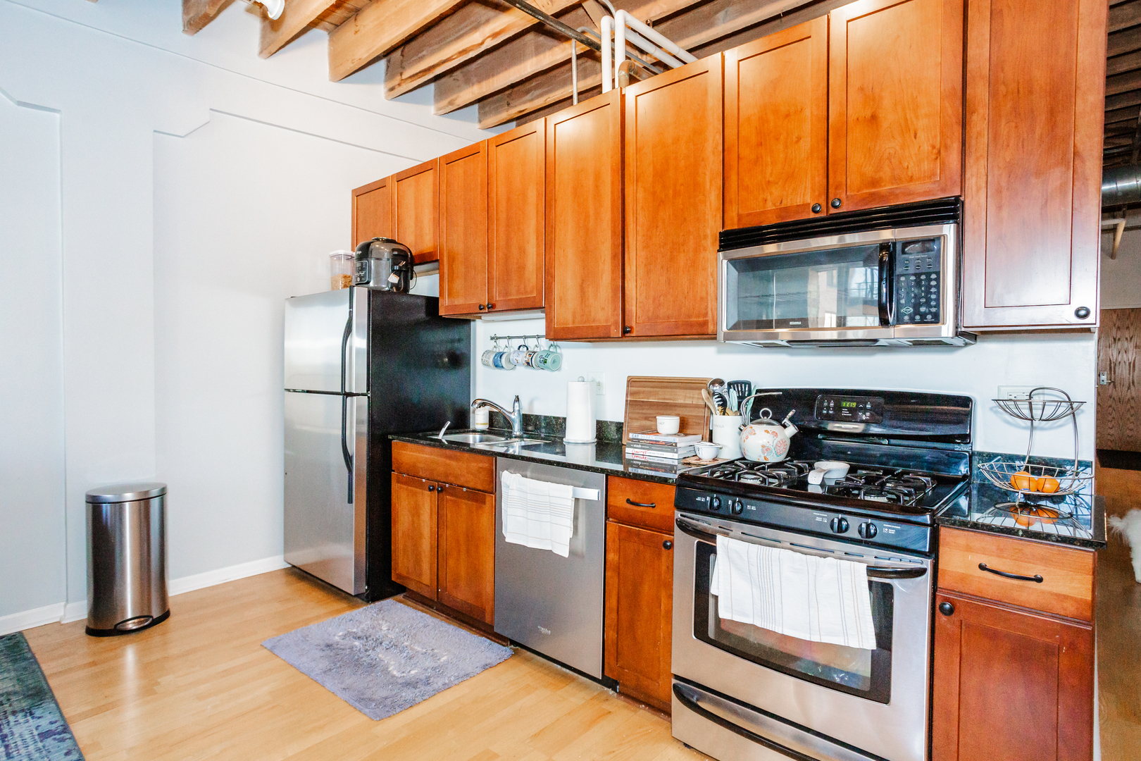 1503 South State Street, Unit 810 Chicago, IL 60605 - Photo 7 of 16 a kitchen with stainless steel appliances granite countertop a refrigerator a stove and a sink with wooden floor
