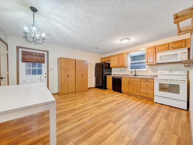 a large white kitchen with stainless steel appliances granite countertop a stove and cabinets