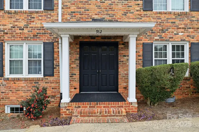 front view of a brick house with a window and potted plants