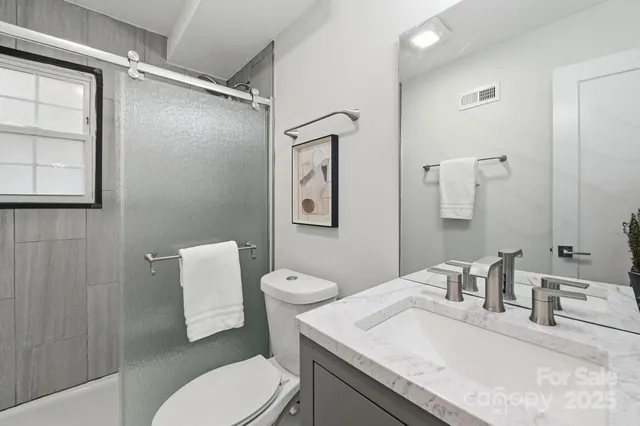 a bathroom with a granite countertop toilet sink and mirror