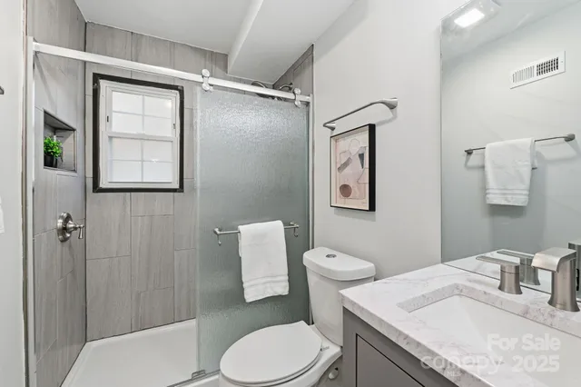 a bathroom with a granite countertop toilet sink and mirror