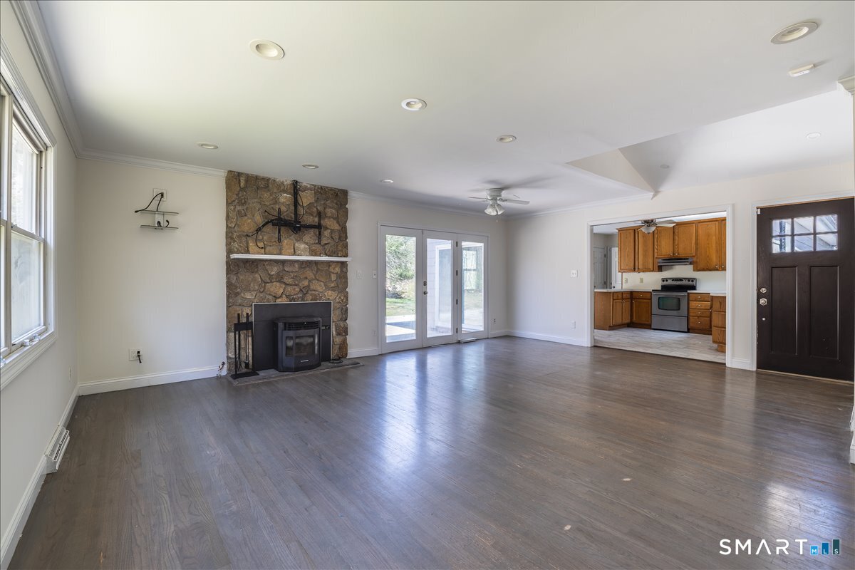 370 Quaker Farms Road Southbury, CT 06488 - Photo 5 of 35 an empty room with wooden floor fireplace and windows