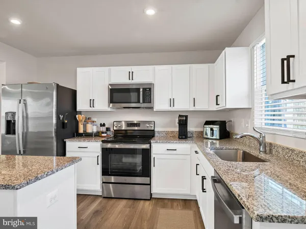 a kitchen with granite countertop a sink a counter top space stainless steel appliances and cabinets