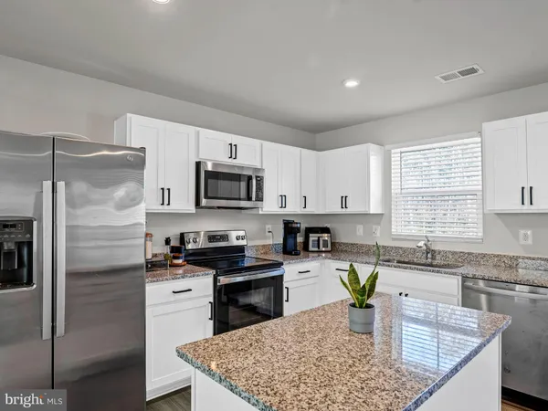 a kitchen with stainless steel appliances granite countertop sink stove refrigerator and cabinets