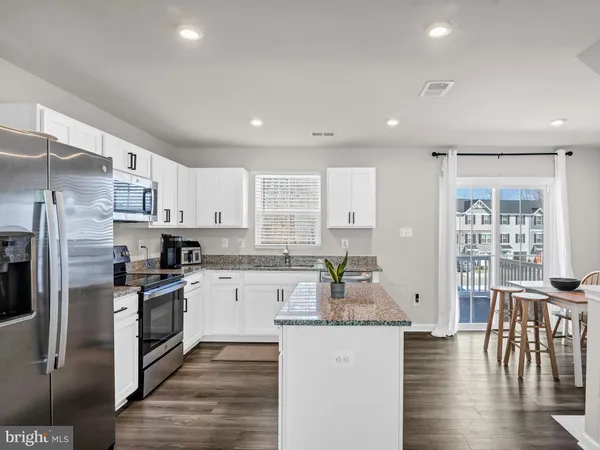an open kitchen with granite countertop kitchen island wooden floor center island and stainless steel appliances
