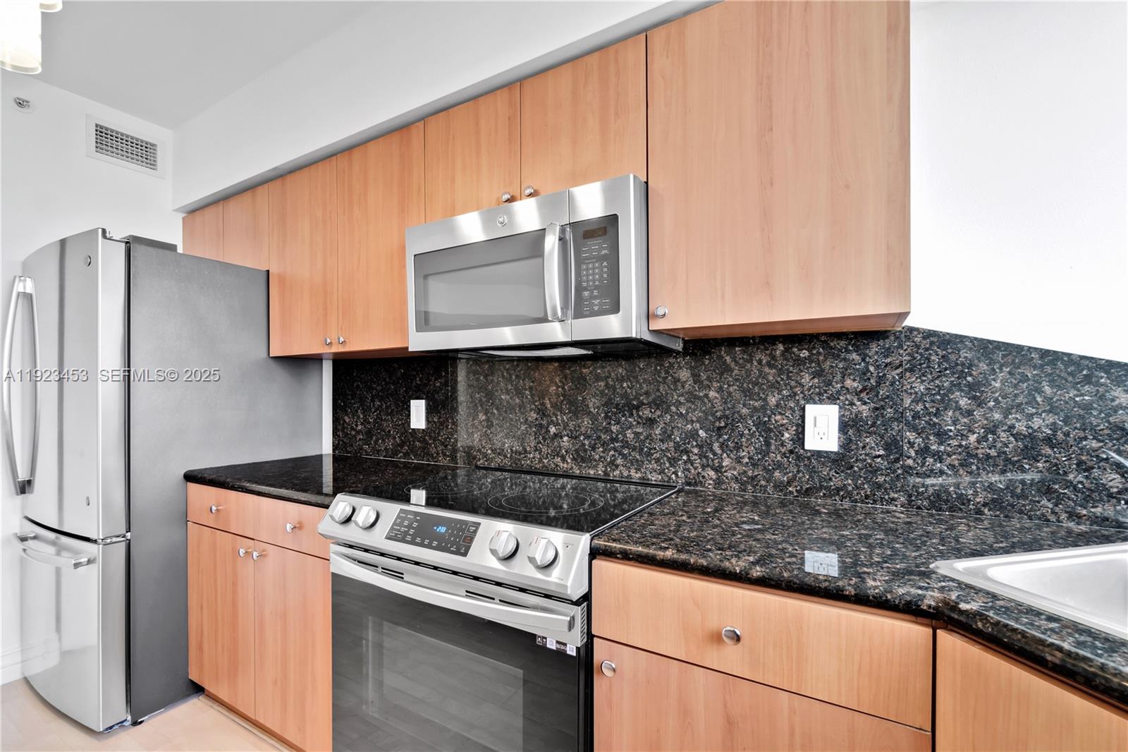 1330 West Avenue, Unit 1009 Miami Beach, FL 33139 - Photo 12 of 43 a kitchen with granite countertop a sink stove and refrigerator