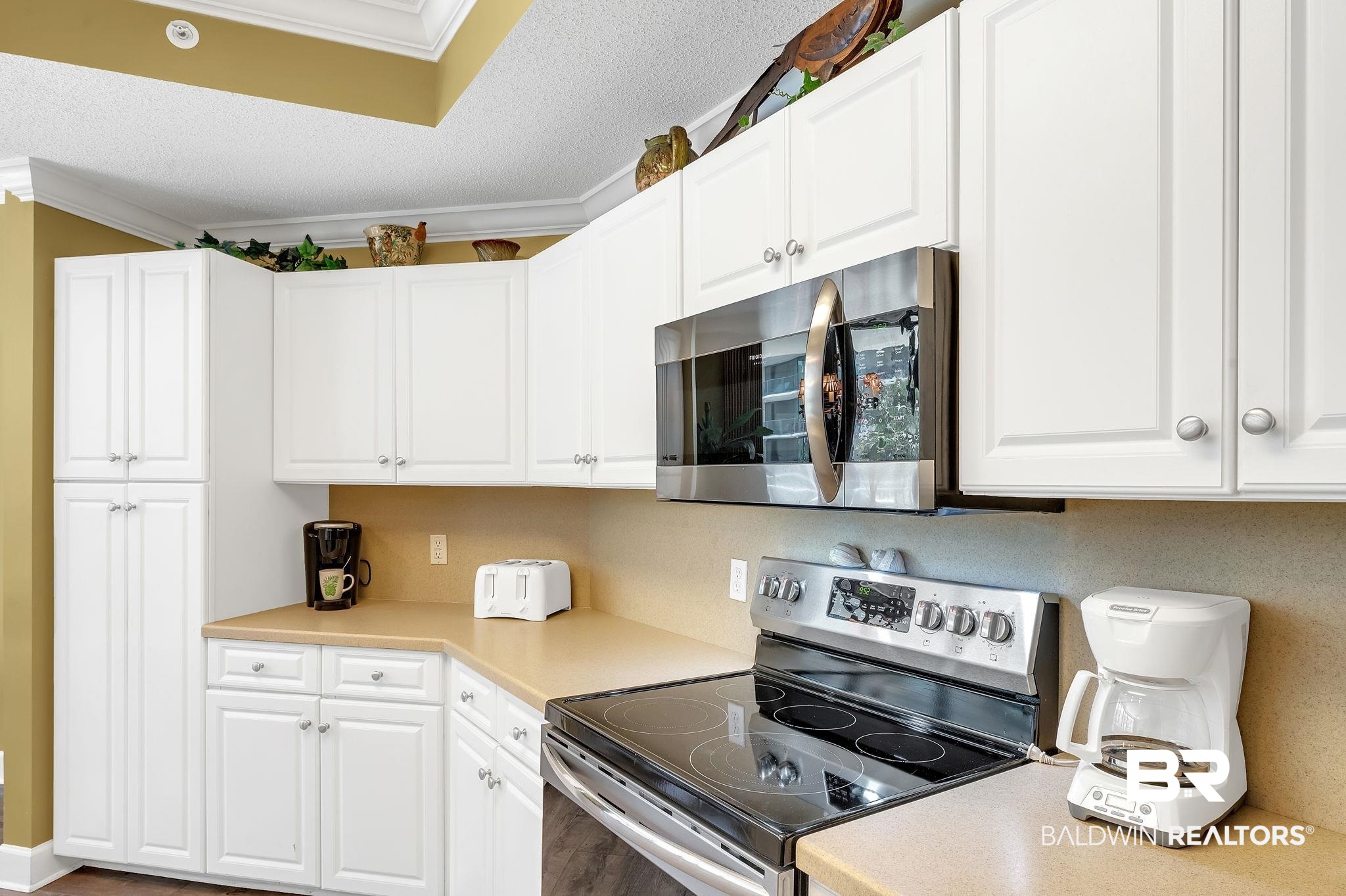27580 Canal Road, Unit 1214 AND BOAT SLIP #62 Orange Beach, AL 36561 - Photo 20 of 67 Kitchen with white cabinetry, appliances with stainless steel finishes, and ornamental molding
