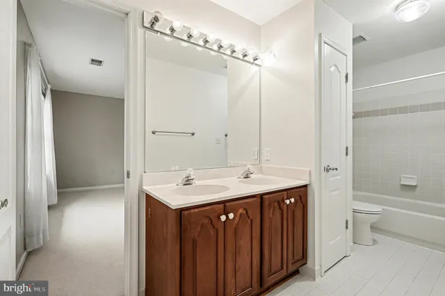 a bathroom with a double vanity sink toilet mirror and bathtub