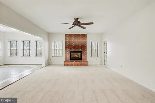 an empty room with windows fireplace and fan