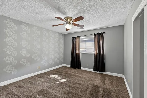 a view of empty room with wooden floor and ceiling fan