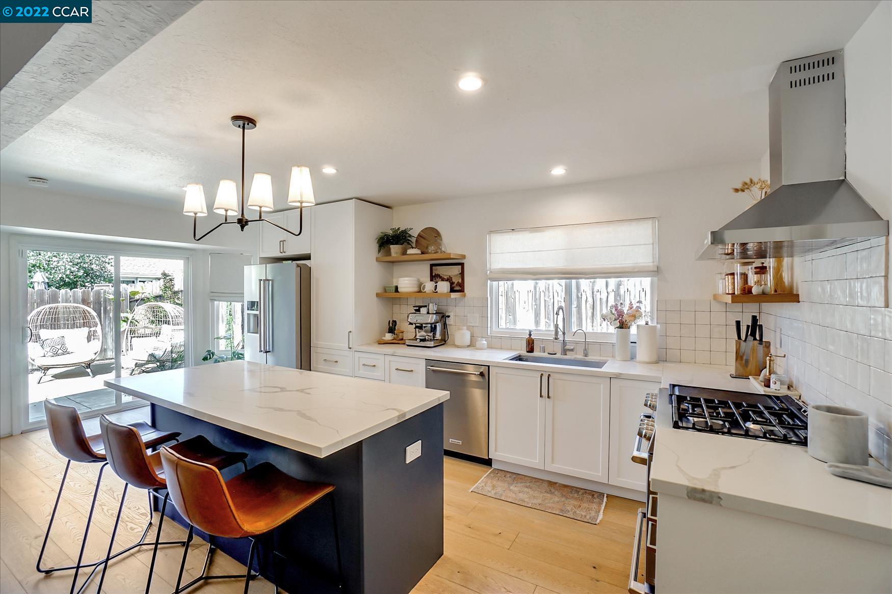 a kitchen with granite countertop a stove a sink a dining table and chairs