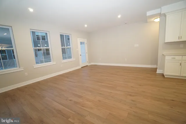 a view of an empty room with window and wooden floor