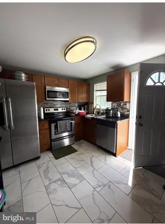 a kitchen with stainless steel appliances granite countertop a refrigerator a stove a sink and a microwave