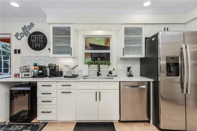 a kitchen with stainless steel appliances granite countertop a refrigerator oven a sink dishwasher and white cabinets with wooden floor