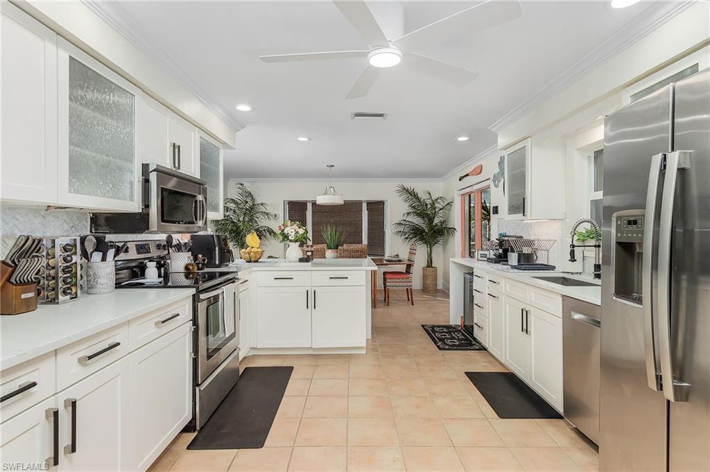 2950 Coach House Lane Naples, FL 34105 - Photo 22 of 50 a kitchen with stainless steel appliances granite countertop a refrigerator oven a sink dishwasher and white cabinets with wooden floor
